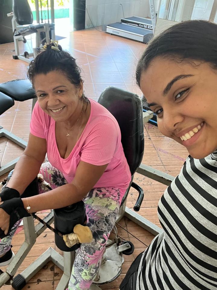 Lis e uma aluna sorrindo durante o treino em aparelho