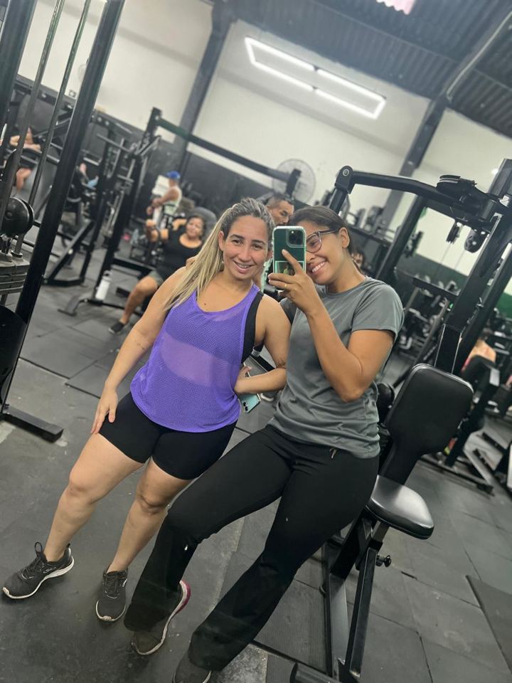 Lis e uma aluna sentadas em um aparelho de musculação